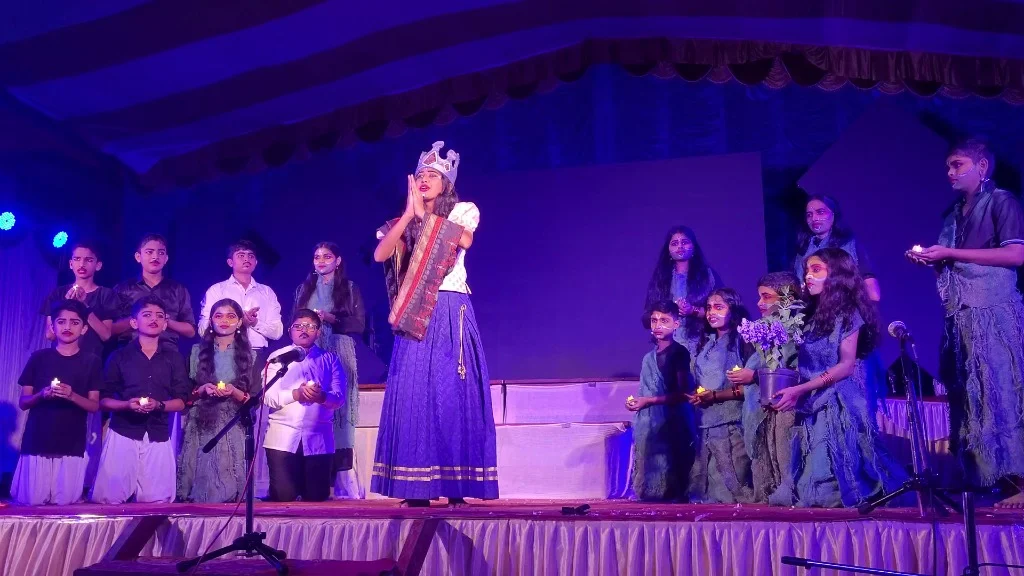 Island Queen in traditional attire with choir holding candles in Mayadveepa